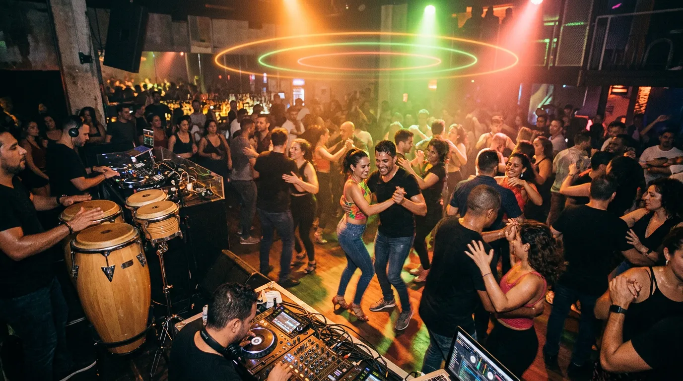 A packed Latin club at night with dancers in fast footwork, conga drums and a DJ booth glowing orange and green, faint light rings floating above the crowd.